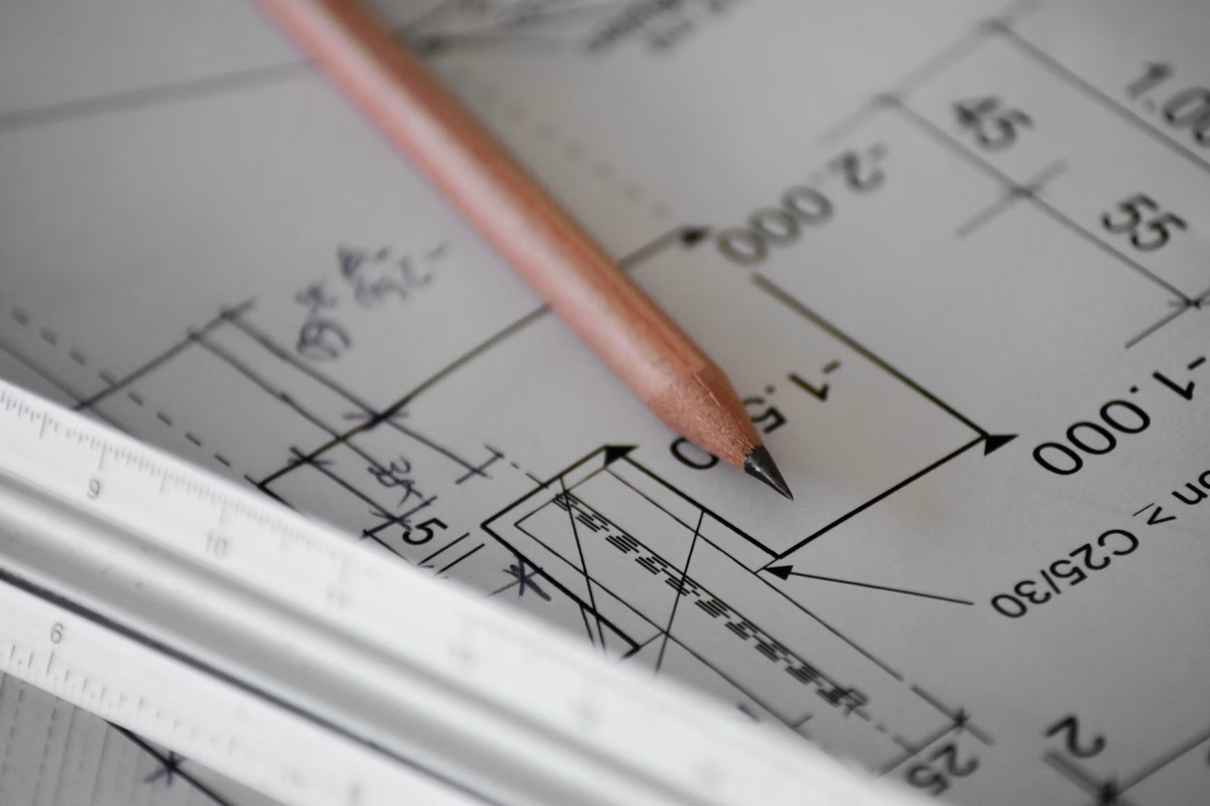 Close-up of a pencil and an engineer's scale on a dimensioned architectural detail drawing.